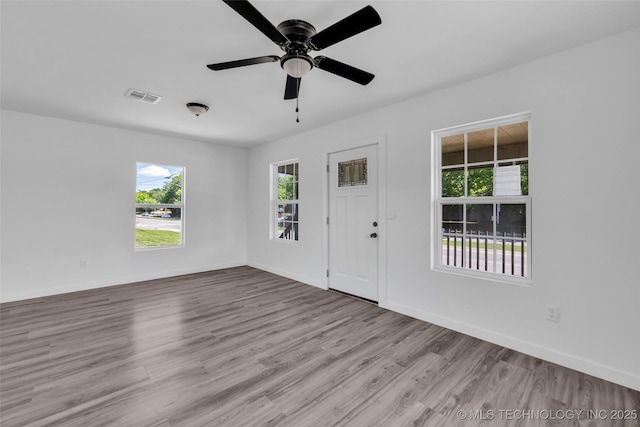 empty room with visible vents, wood finished floors, baseboards, and ceiling fan