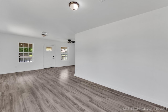 interior space featuring ceiling fan, baseboards, and wood finished floors