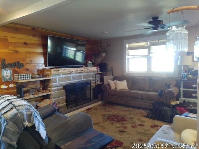 living area featuring a stone fireplace and ceiling fan