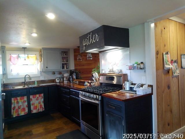 kitchen featuring stainless steel gas range oven, recessed lighting, under cabinet range hood, a sink, and dark wood-type flooring