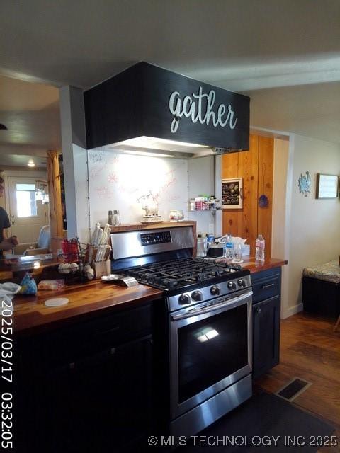 kitchen with stainless steel range with gas cooktop, wood finished floors, visible vents, and wood counters