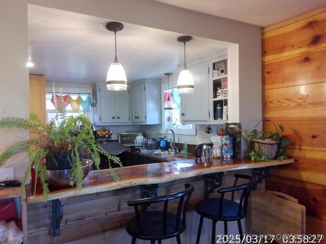 kitchen featuring a peninsula, a breakfast bar area, pendant lighting, and a sink