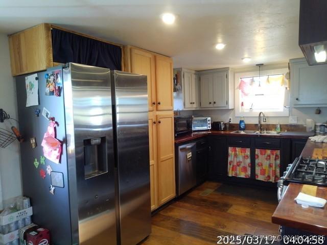 kitchen with a sink, dark countertops, stainless steel appliances, dark wood-style flooring, and recessed lighting