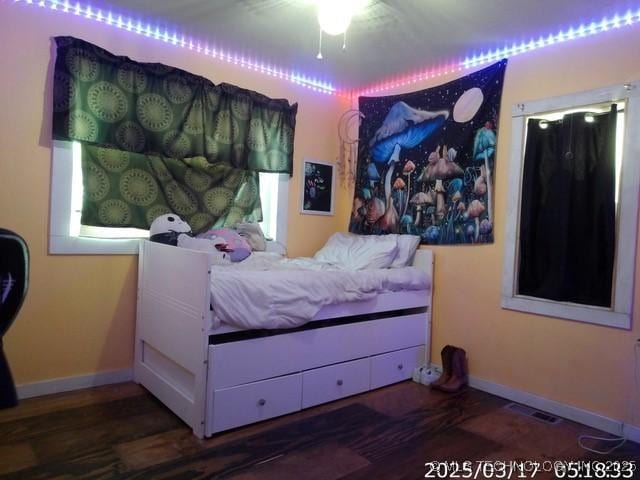 bedroom with wood finished floors, visible vents, and baseboards