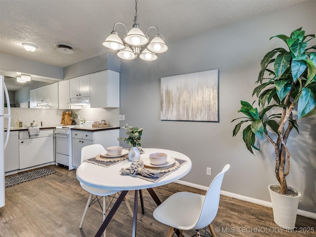 dining room with an inviting chandelier, a textured ceiling, wood finished floors, and baseboards