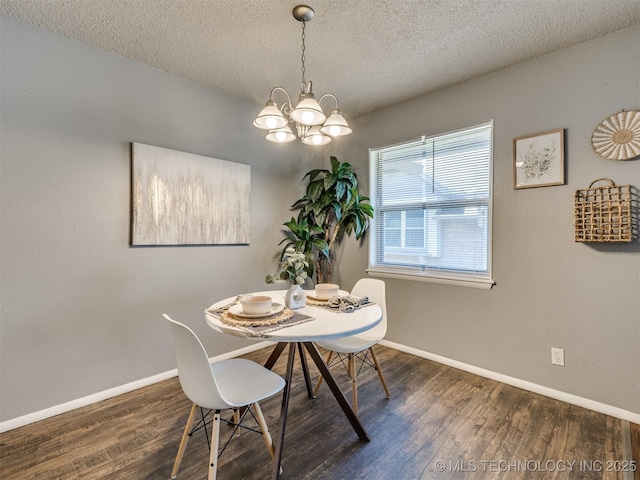 dining space featuring dark wood-style flooring, a textured ceiling, baseboards, and a chandelier