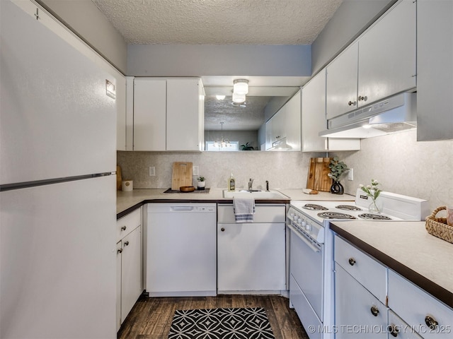 kitchen featuring a textured ceiling, under cabinet range hood, white appliances, a sink, and dark wood-style floors