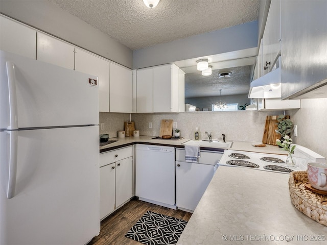 kitchen featuring a textured ceiling, white appliances, light countertops, and a sink
