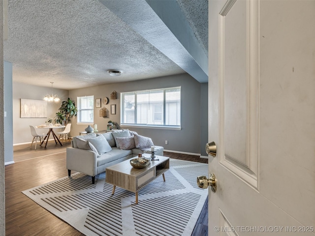living room featuring wood finished floors, a chandelier, baseboards, and a textured ceiling