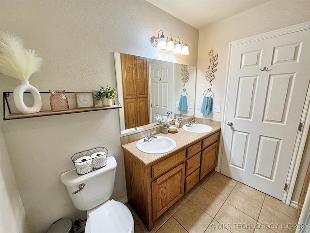 bathroom with double vanity, toilet, tile patterned flooring, and a sink