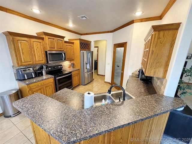 kitchen with a peninsula, tasteful backsplash, visible vents, arched walkways, and appliances with stainless steel finishes