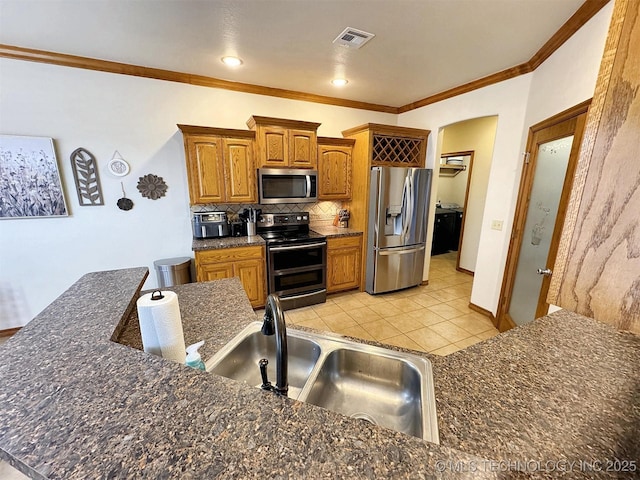 kitchen featuring brown cabinets, a sink, stainless steel appliances, backsplash, and ornamental molding