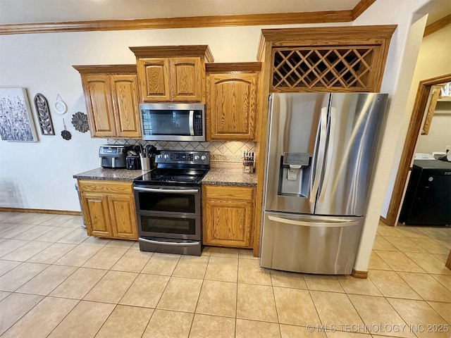 kitchen featuring light tile patterned floors, baseboards, washer / dryer, decorative backsplash, and appliances with stainless steel finishes