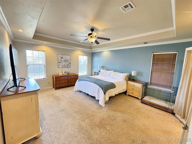 bedroom featuring multiple windows, light carpet, a tray ceiling, and visible vents
