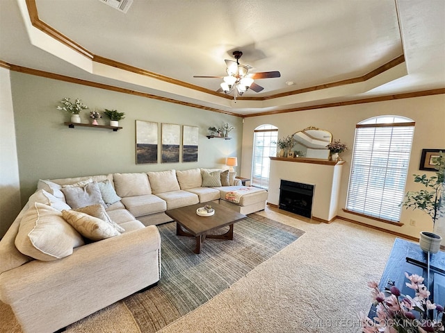 carpeted living room with a raised ceiling, a fireplace with flush hearth, and crown molding