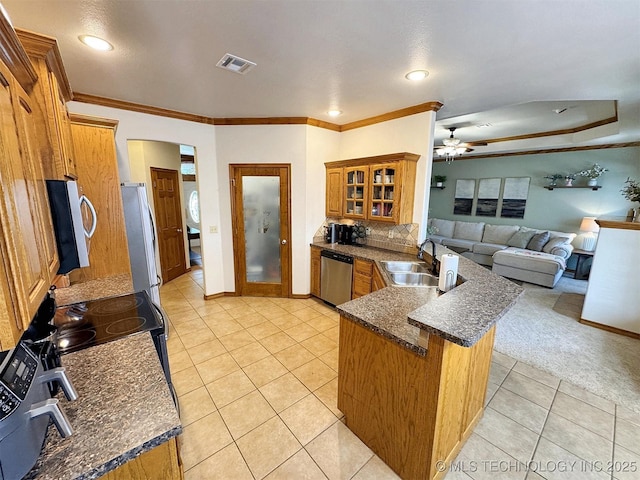 kitchen with a sink, a peninsula, stainless steel appliances, brown cabinetry, and light tile patterned floors