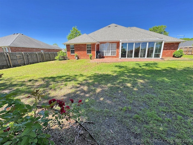 rear view of property featuring a fenced backyard, brick siding, and a yard