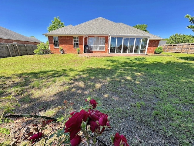 rear view of property featuring a lawn, brick siding, and a fenced backyard