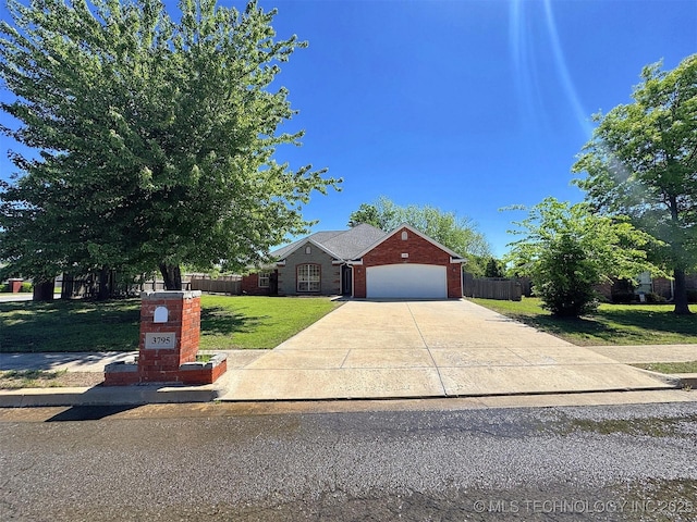 view of front of property with driveway, brick siding, fence, an attached garage, and a front yard