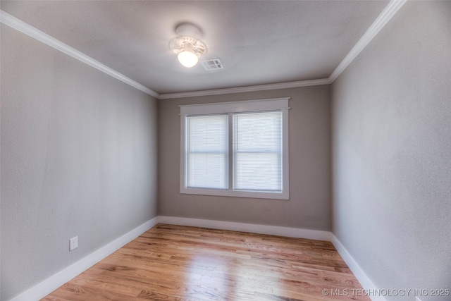 spare room with crown molding, baseboards, visible vents, and wood finished floors