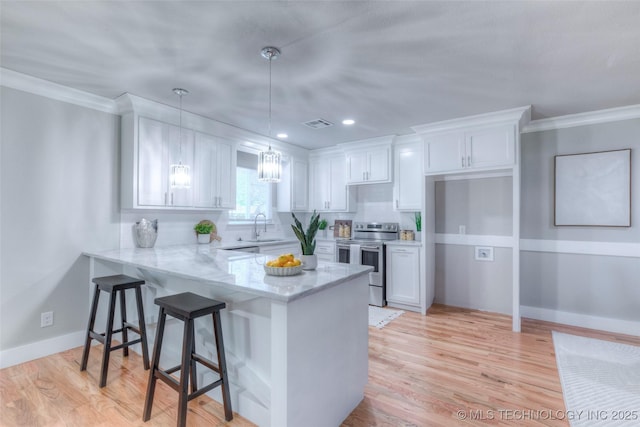 kitchen with a sink, a peninsula, stainless steel electric range oven, white cabinets, and light stone countertops