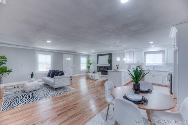 dining space with light wood-style floors, crown molding, plenty of natural light, and recessed lighting
