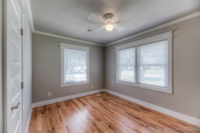 spare room with a ceiling fan, baseboards, ornamental molding, visible vents, and wood finished floors