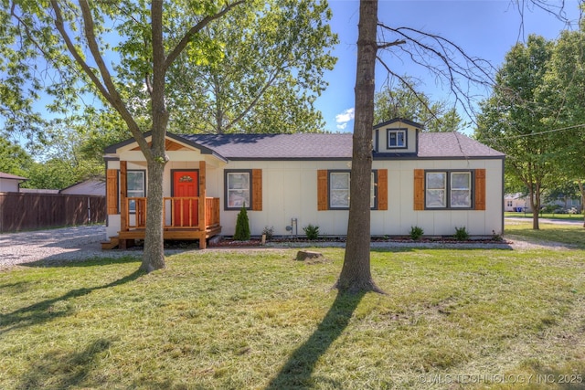 view of front of house featuring roof with shingles, fence, a front yard, and board and batten siding