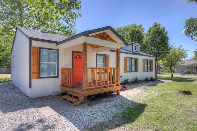bungalow featuring board and batten siding, a shingled roof, and a front yard