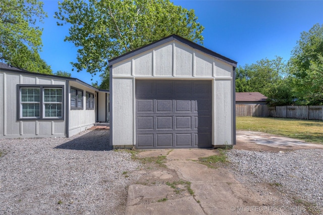 detached garage featuring driveway and fence