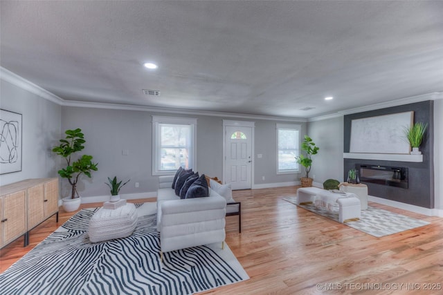 living area with baseboards, light wood finished floors, and crown molding