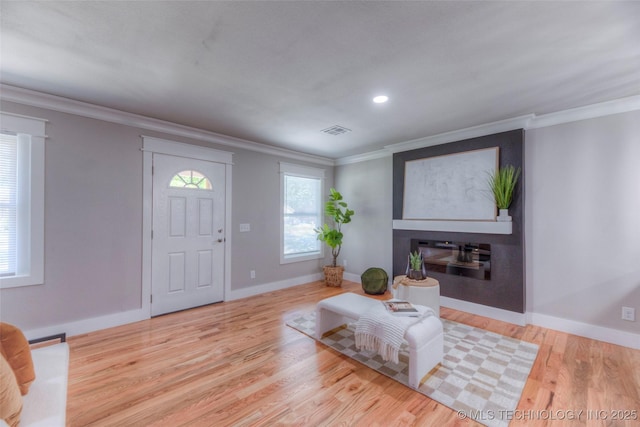 living room featuring a large fireplace, ornamental molding, visible vents, and wood finished floors