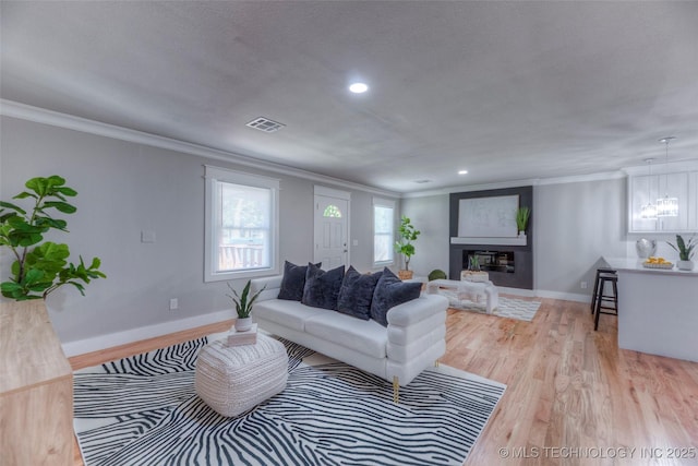 living room featuring crown molding, visible vents, wood finished floors, and baseboards