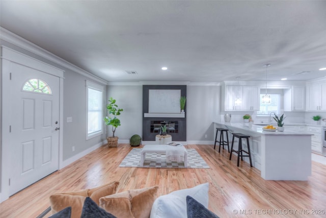 living room with a healthy amount of sunlight, crown molding, and visible vents