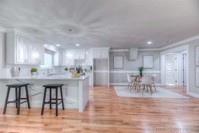 kitchen with a peninsula, recessed lighting, a kitchen bar, and white cabinets