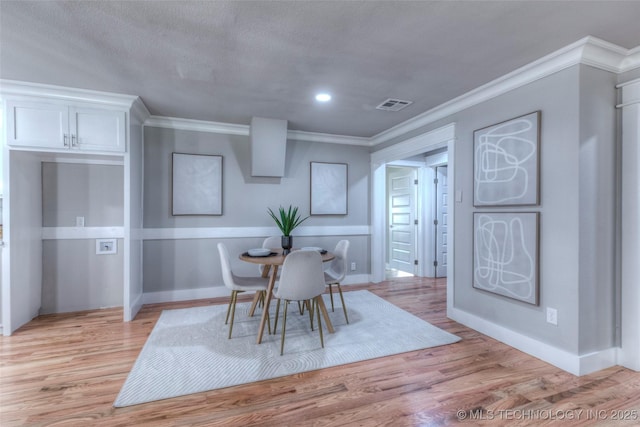 dining space featuring light wood finished floors, crown molding, visible vents, and recessed lighting
