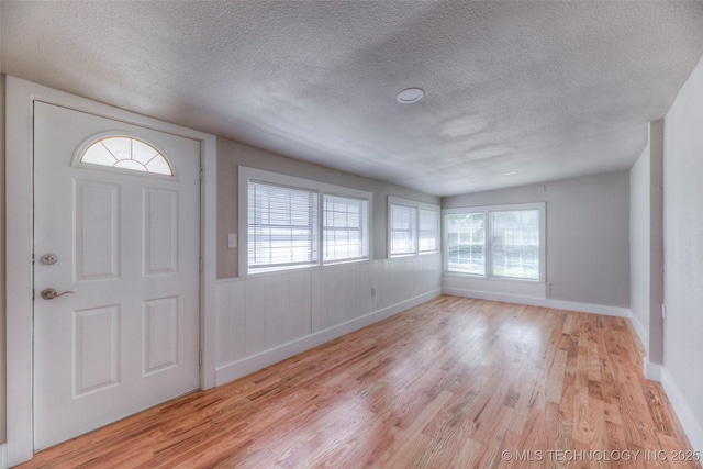 entryway with baseboards, light wood-style flooring, and a textured ceiling