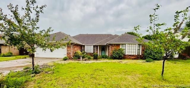 single story home with an attached garage, a front lawn, and brick siding