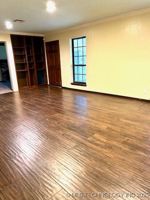 unfurnished living room with wood finished floors, baseboards, and ornamental molding