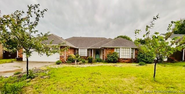 ranch-style house featuring concrete driveway, an attached garage, brick siding, and a front yard