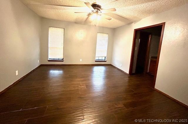 spare room with a textured ceiling, dark wood-type flooring, baseboards, and ceiling fan