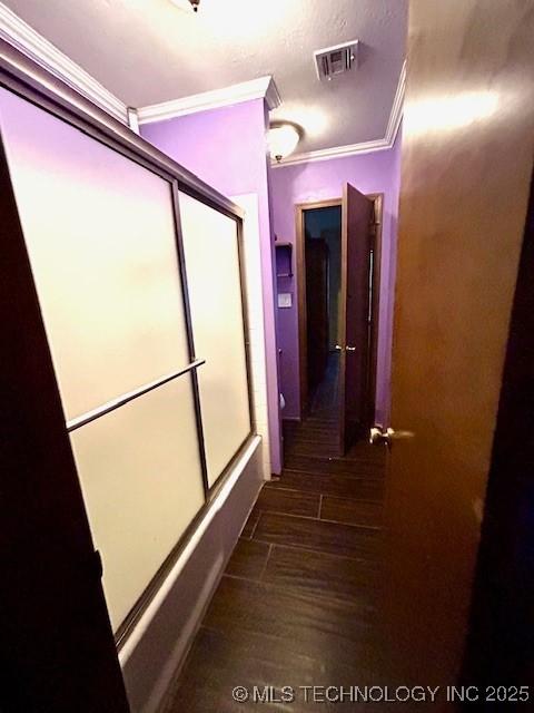 bathroom featuring ornamental molding, combined bath / shower with glass door, visible vents, and wood finished floors