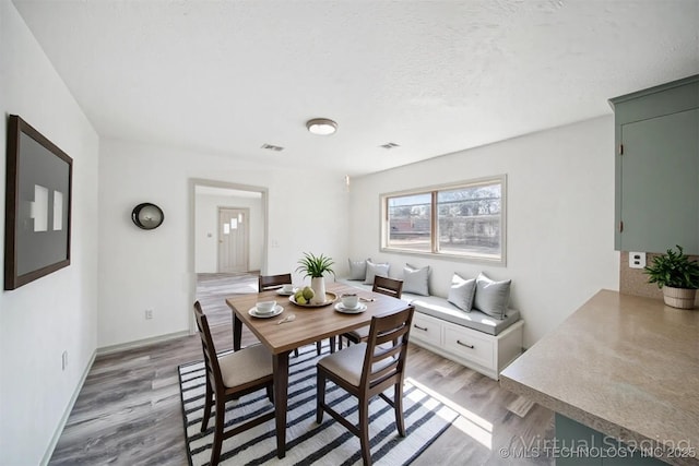 dining room featuring baseboards, light wood-type flooring, and visible vents