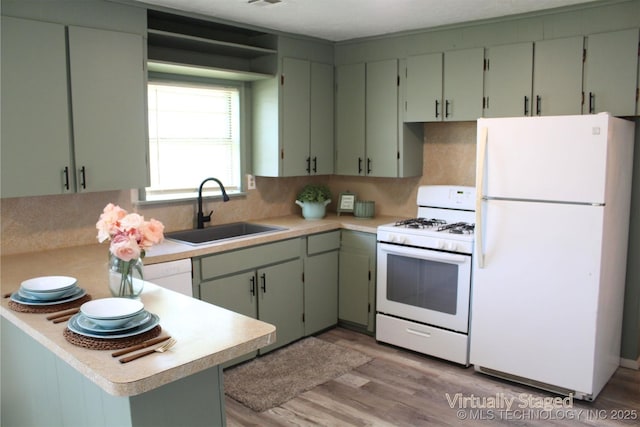 kitchen with a sink, white appliances, light countertops, and light wood-type flooring