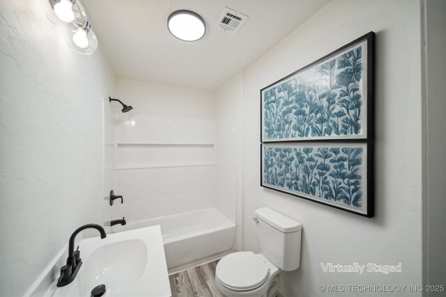 full bath with toilet, wood finished floors, a sink, shower / washtub combination, and visible vents
