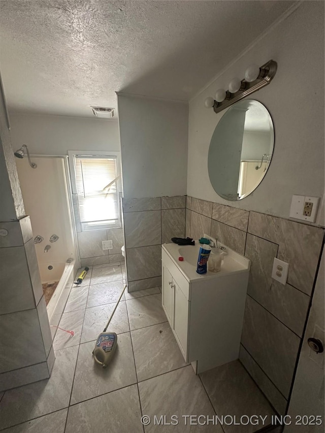 417 E SE, Ardmore, OK 73401 - bathroom with tile walls, a stall shower, a textured ceiling, and wainscoting