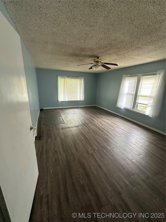 417 E SE, Ardmore, OK 73401 - spare room with a textured ceiling, dark wood-type flooring, a ceiling fan, healthy amount of natural light, and baseboards