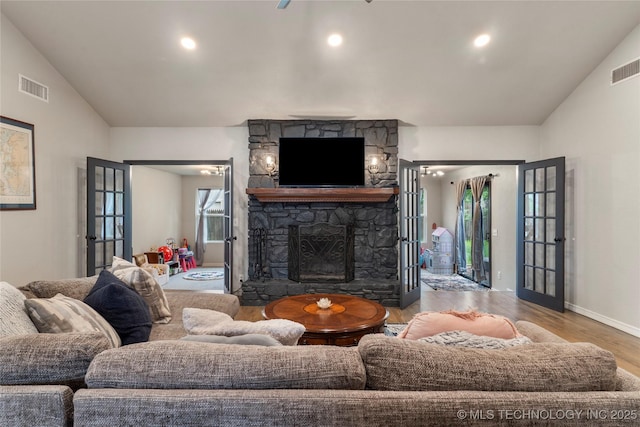 living area with wood finished floors, visible vents, vaulted ceiling, a fireplace, and baseboards