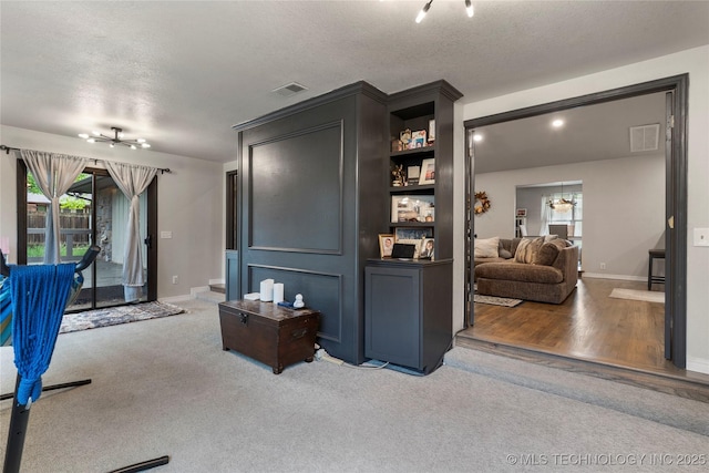 carpeted living area with baseboards, an inviting chandelier, visible vents, and a textured ceiling