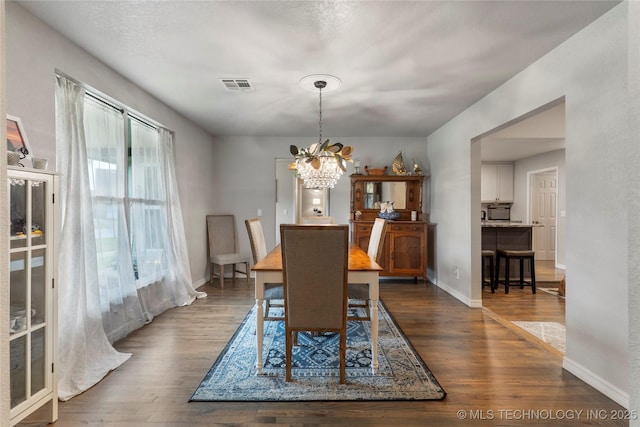 dining area featuring baseboards, an inviting chandelier, visible vents, and wood finished floors